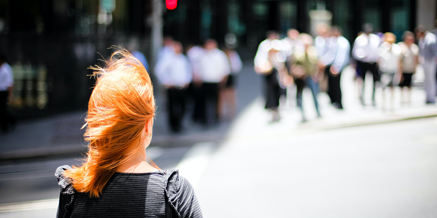 woman with red hair crossing city street